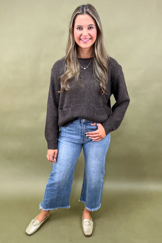 Dark brown cozy knit sweater with front pockets paired with light wash wide leg frayed hem jeans and gold loafers