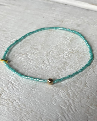 Turquoise beaded necklace with a gold clasp on a light gray surface