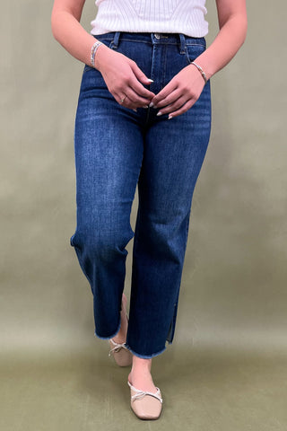 Person wearing blue jeans and a white top on a plain background