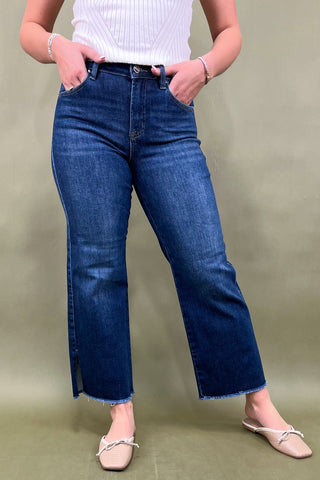 Person wearing blue jeans and a white top on a green background