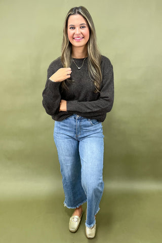Dark brown cozy knit sweater with front pockets paired with light wash wide leg frayed hem jeans and gold loafers