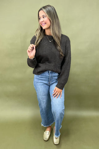 Dark brown cozy knit sweater with front pockets paired with light wash wide leg frayed hem jeans and gold loafers