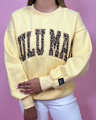 Yellow sweatshirt with leopard print text on a pink background