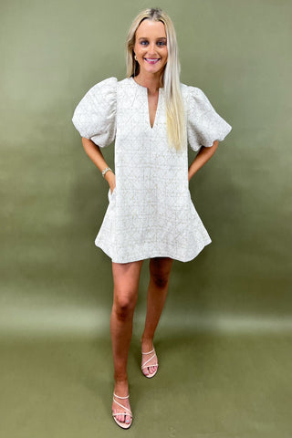 Woman wearing a white dress with puff sleeves against a green background