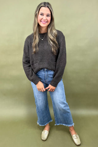 Dark brown cozy knit sweater with front pockets paired with light wash wide leg frayed hem jeans and gold loafers