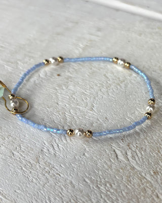 Delicate beaded bracelet with small pearls and gold accents on a light background