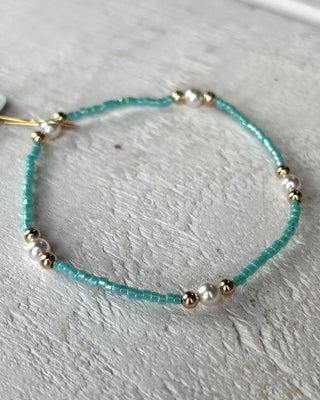 Bracelet with turquoise beads and gold accents on a light gray surface