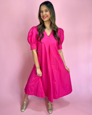 Woman wearing a bright pink dress against a pink background