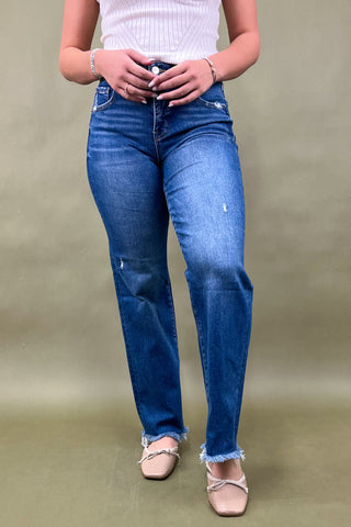 Person wearing blue jeans and a white top on a beige background