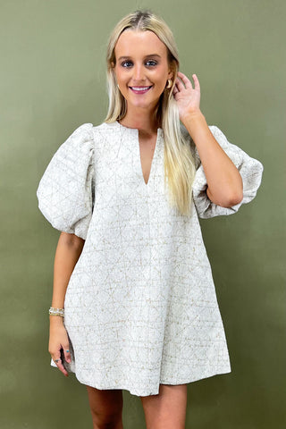 Woman wearing a white patterned dress against a green background