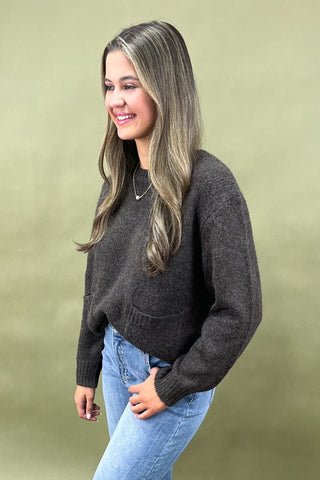 Dark brown cozy knit sweater with front pockets paired with light wash wide leg frayed hem jeans and gold loafers