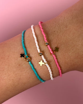 Three colorful beaded bracelets on a wrist against a pink background