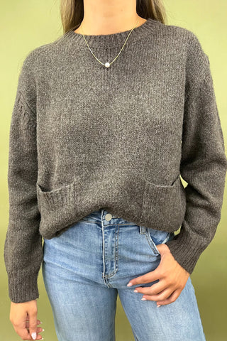 Dark brown cozy knit sweater with front pockets paired with light wash wide leg frayed hem jeans and gold loafers