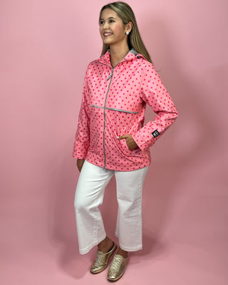 Woman wearing a pink polka dot jacket on a pink background