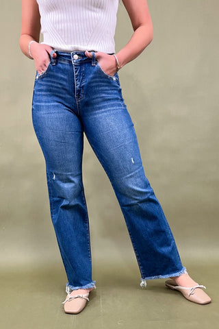 Person wearing blue jeans and a white top on a plain background