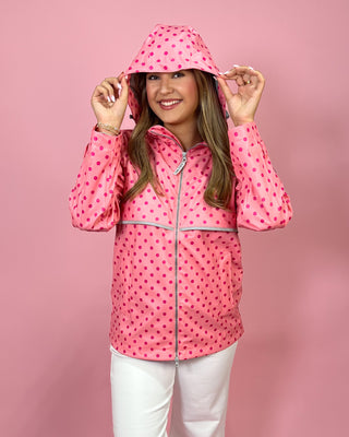 Person wearing a pink raincoat with a hood on a pink background