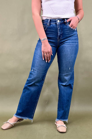 Person wearing blue jeans and a white top on a beige background