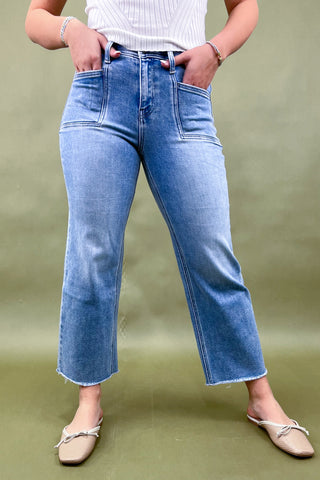 Person wearing light blue jeans on a green background