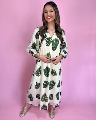 Woman wearing a white dress with green leaf patterns against a pink background