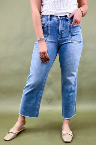 Person wearing light blue jeans on a green background