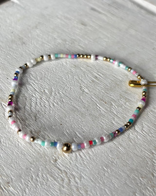 Beaded bracelet with multicolor beads on a light gray surface
