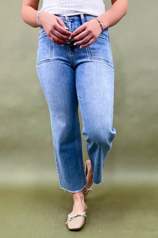 Person wearing light blue jeans on a green background