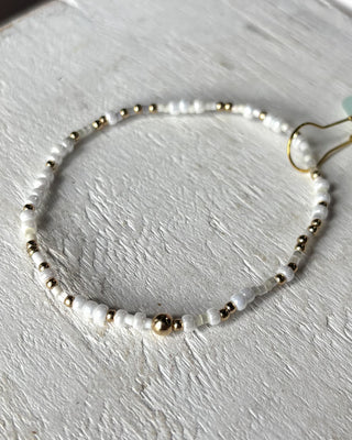 Bracelet with white beads and gold accents on a light gray surface