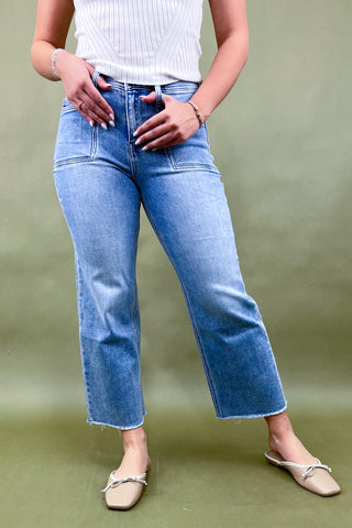 Person wearing blue jeans and a white top on a green background
