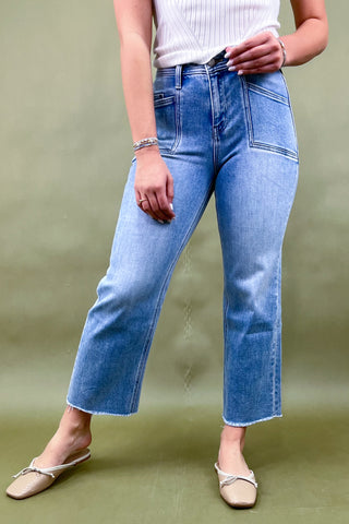 Person wearing blue jeans and a white top on a green background