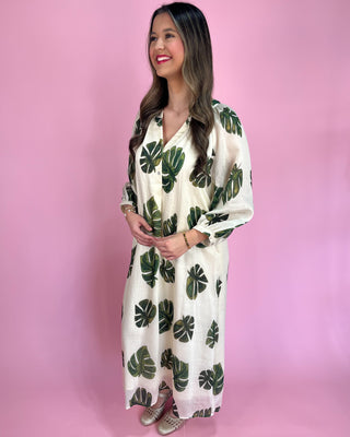 Woman wearing a white dress with green leaf patterns against a pink background