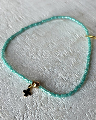 Turquoise beaded necklace with a gold clasp on a light gray background