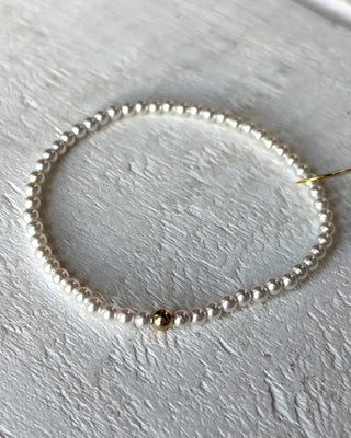 Pearl bracelet with a gold clasp on a light wooden surface