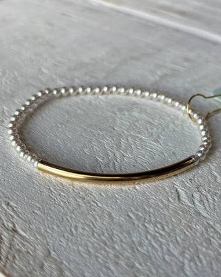 Bracelet with gold bar and pearl-like beads on a light gray background