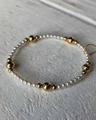 Bracelet with gold and white beads on a light gray background