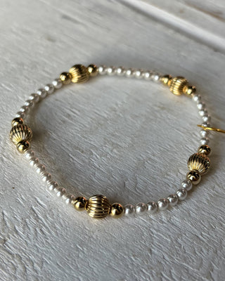 Bracelet with gold and pearl beads on a light wooden surface