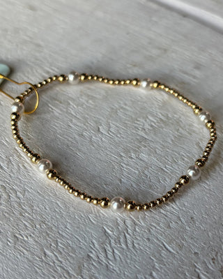 Gold and pearl beaded hairband on a light gray background