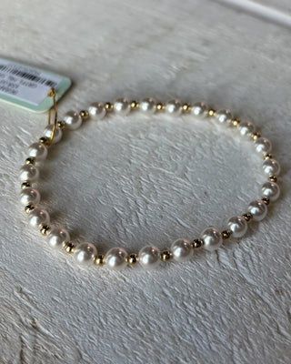 Pearl bracelet with gold accents on a light wooden surface