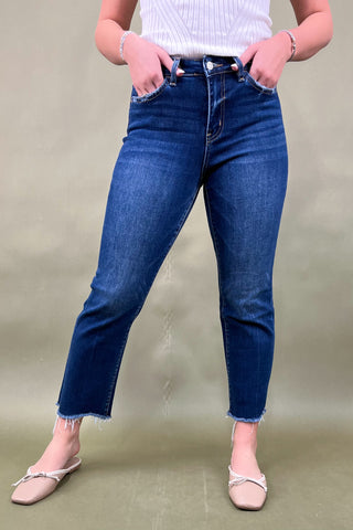 Person wearing blue jeans and a white top on a beige background