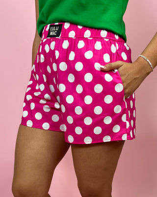 Pink polka dot shorts with white dots on a pink background