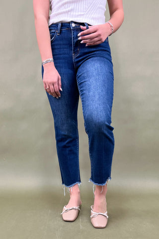 Person wearing blue jeans and a white top against a plain background