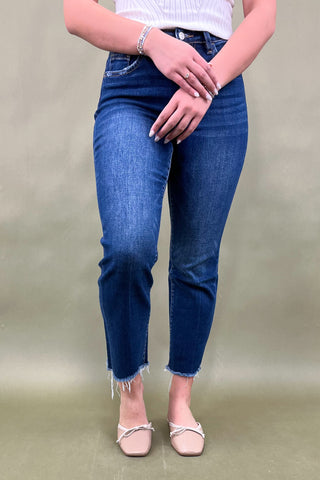 Person wearing blue jeans and a white top on a plain background
