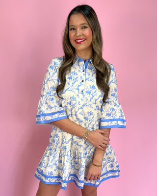 Woman wearing a floral dress with blue accents against a pink background