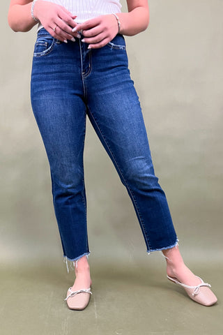 Person wearing blue jeans and a white top on a plain background