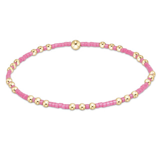 Pink beaded bracelet with gold accents on a white background