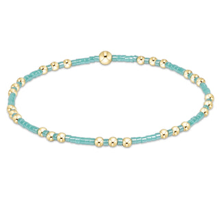 Turquoise and gold beaded bracelet on a white background
