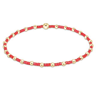 Bracelet with red beads and gold accents on a white background