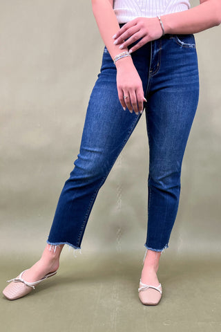Person wearing blue jeans and white sandals on a plain background