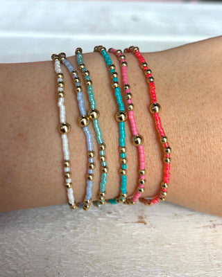 Set of colorful beaded bracelets on a wrist with a neutral background