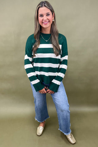 Green and white striped knit sweater styled with light wash wide leg frayed hem jeans and gold loafers