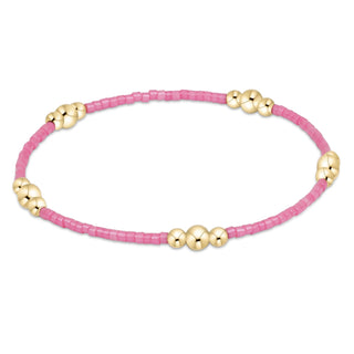 Pink beaded bracelet with gold beads on a white background